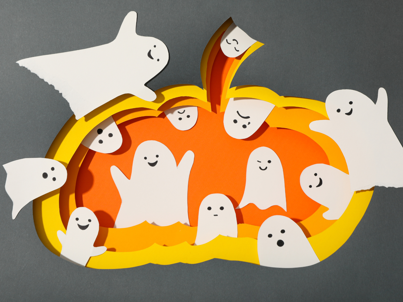 Une citrouille faite en papier et des fantômes devant et dedans
